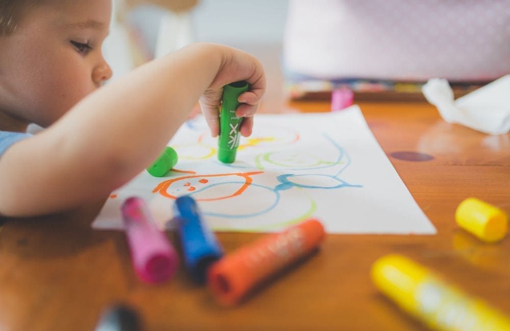 childcare young child drawing on a piece of paper with markers in childcare